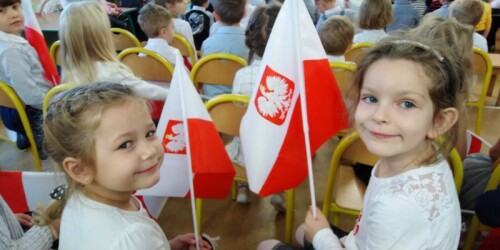 dwie dziewczynki pozują do zdjęcia z flagami
