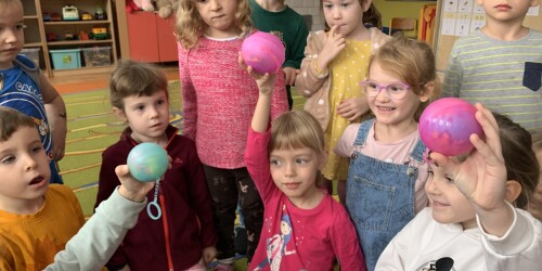dzieci prezentują swoje nowe zabawki resorek, balony i piłeczkę