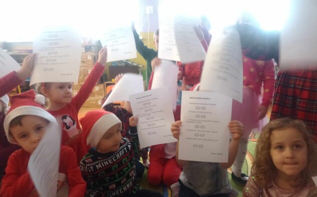 Dzieci pokazują kartkę z zadaniami od Mikołaja