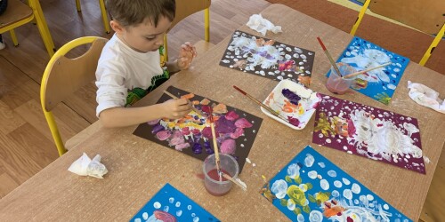 chłopiec maluje obrazek wieloma kolorami