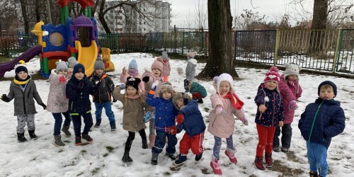 dzieci bawią się w śniegu na na placu zabaw