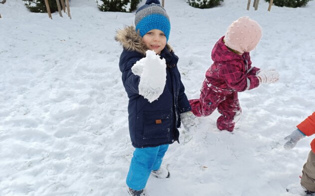 chłopiec trzyma ulepioną kulkę śnieżną