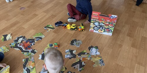 dzieci układają puzzle tworzące trasę dla samochodów