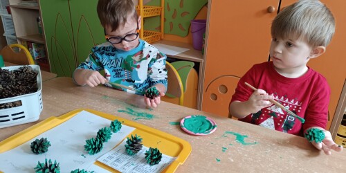 chłopcy malują szyszki zieloną farbą