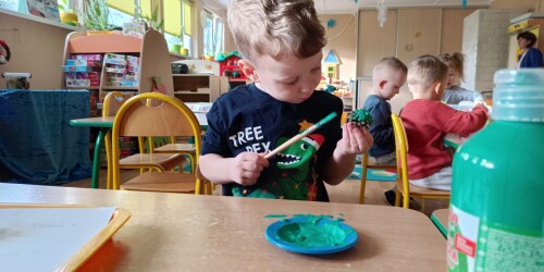 chłopiec maluje szyszkę zieloną farbą
