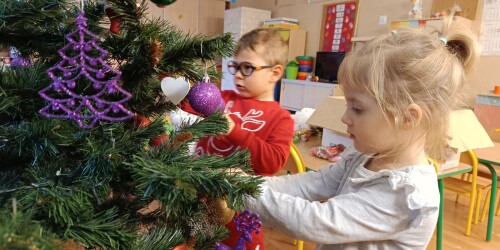 dzieci wieszają na choince świąteczne ozdoby