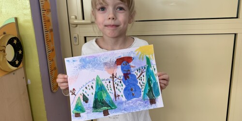 dziewczynka prezentuje namalowany obrazek przedstawiający zimowe drzewa