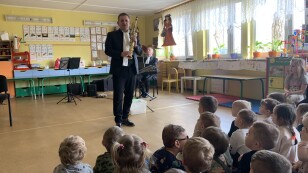muzyk prezentuje siedzącym dzieciom saksofon