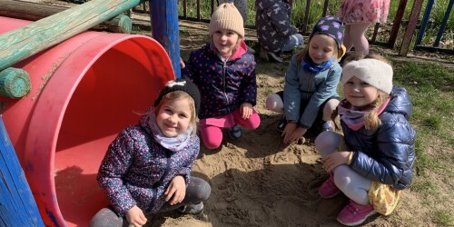 dziewczynki bawią się na piasku obok czerwonej tuby