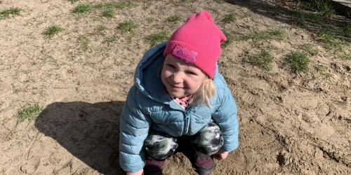 dziewczynka kucnęła na piasku