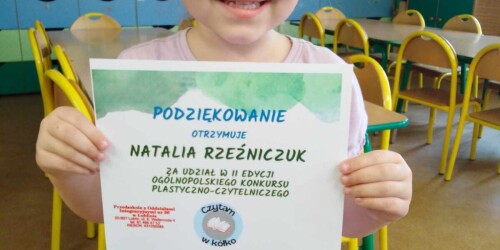Dziewczynka prezentuje dyplom za udział w konkursie